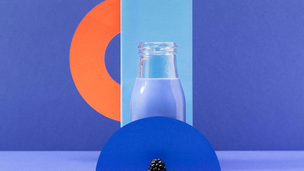 front view blue smoothie glass bottle with blackberries